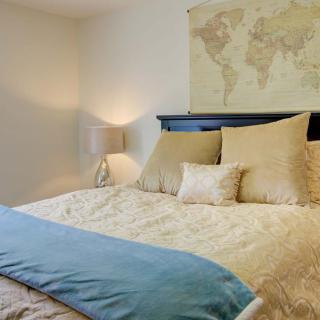 A cozy bedroom with a world map decoration above the bed and soft lighting.