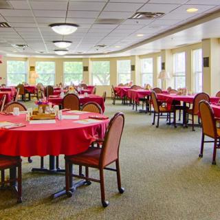 An elegant dining room with red tablecloths and neatly arranged tables.