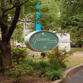 A green sign surrounded by trees and plants in an outdoor setting.