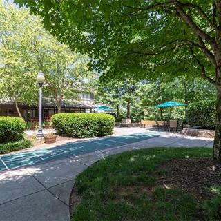 A peaceful garden area with a winding pathway, surrounded by lush greenery and shaded benches.