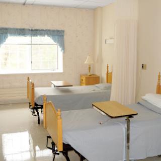 A well-lit hospital patient room with two beds and a view.