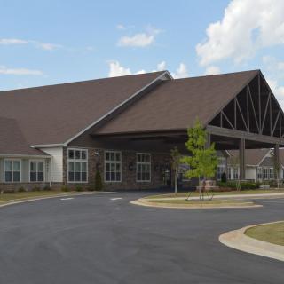 A large building with a peaked roof and surrounding driveway under a partly cloudy sky.