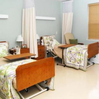 A clean and well-organized hospital room with two adjustable medical beds separated by privacy curtains.