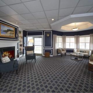 A cozy lobby with a fireplace and comfortable seating areas, accented by large windows and artwork.