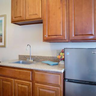 A cozy kitchen featuring wooden cabinets, a functional sink, and a refrigerator.