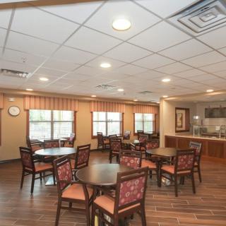 A cozy dining area with round tables, chairs, and warm lighting.