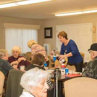 A warm gathering of seniors enjoying food and conversation in a community setting.