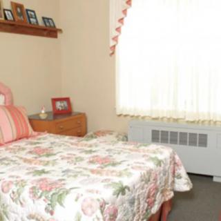 A cozy bedroom with a floral bedspread and natural light from the window.