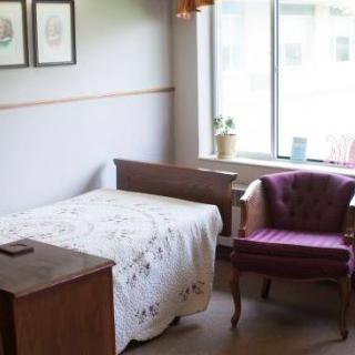 A cozy bedroom with a bed and an upholstered chair by the window.