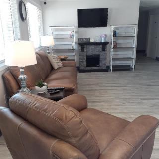 A cozy living room with brown leather sofas, a wall-mounted TV, and ambient lighting.