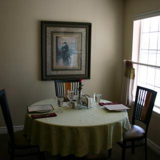 A cozy dining room with a round table and chairs by a window.