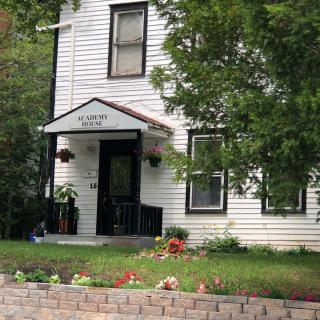 A quaint two-story house with a small garden in the front yard.