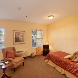 A cozy bedroom with a single bed, armchair, and warm lighting.