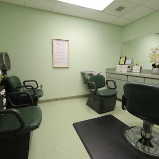 An empty hair salon with green walls and several chairs for clients.