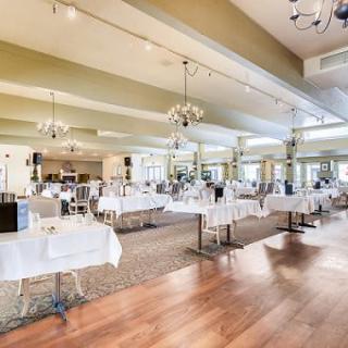 A spacious and elegant restaurant interior with neatly arranged tables and chandeliers.