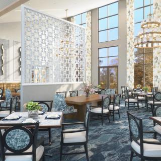 A modern restaurant interior featuring elegant chandeliers, decorative walls, and comfortable seating.