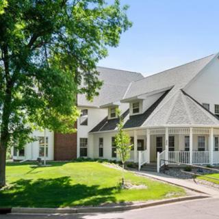 A suburban house with a spacious porch and well-maintained lawn.