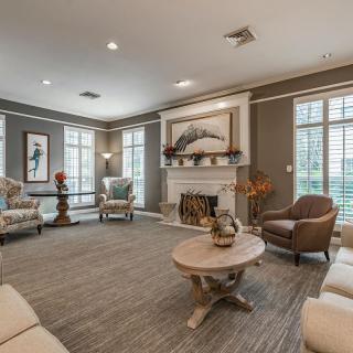 A spacious living room with contemporary decor, featuring a fireplace and large windows.