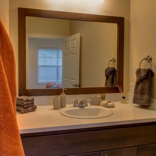 A tidy bathroom with a large mirror above the sink and neatly arranged towels.