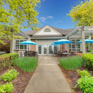 A charming building with outdoor seating and blue umbrellas, surrounded by lush greenery and trees.