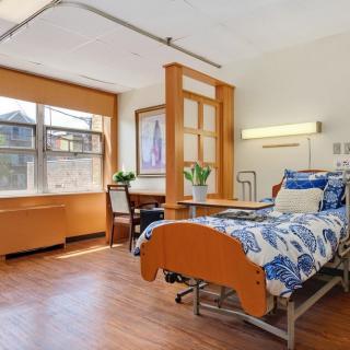A clean and well-lit hospital room with a single bed and large window.