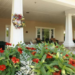 A beautifully landscaped front porch adorned with vibrant flowers and a welcoming wreath.