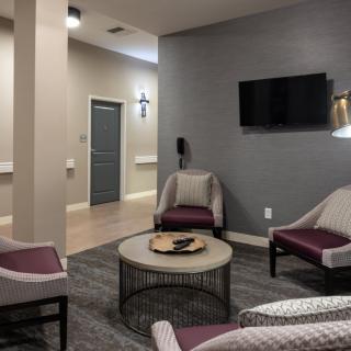 A modern living room with stylish furniture featuring a seating area, wall-mounted television, and a central coffee table.