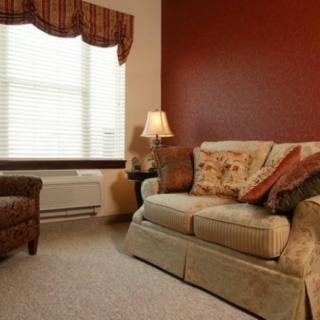 A cozy living room with a sofa, armchair, and warm lighting.