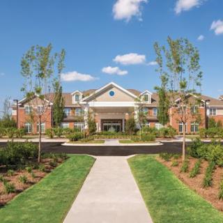 A beautifully landscaped residential building under a clear blue sky.