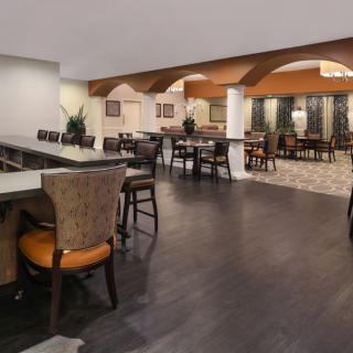 A spacious restaurant interior featuring a blend of modern and classic design elements, with a dining and bar area.