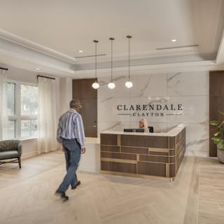 A man approaches the reception desk in a modern lobby with elegant interior design.