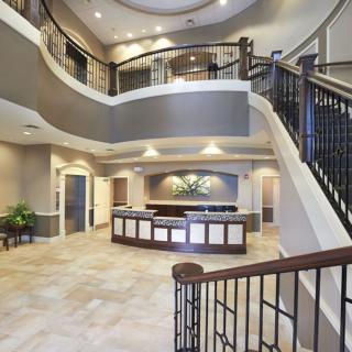 A modern lobby with a reception desk and a grand staircase.