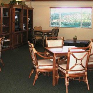 A cozy room featuring several tables and chairs with large bookshelves and a window providing natural light.