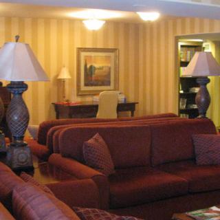 A cozy living room with sofas, lamps, and a desk in the background.