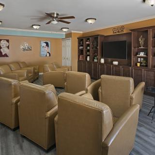 A cozy home theater room featuring comfortable armchairs and a large TV with built-in cabinetry.