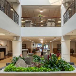 A spacious lobby area featuring an indoor garden with lush plants and elegant architectural design.
