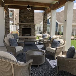 A cozy outdoor patio setup with comfortable wicker chairs and a fireplace under a covered area.