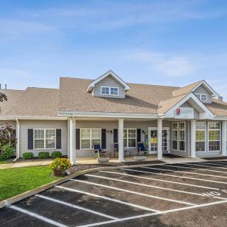 A suburban commercial building with a parking lot on a clear day.