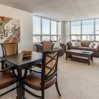 A spacious living and dining area with large windows that allow natural light to fill the modern, well-furnished apartment.