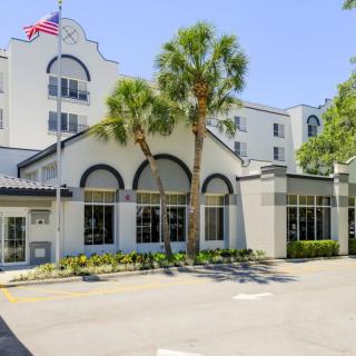 A hotel building with palm trees and an American flag.