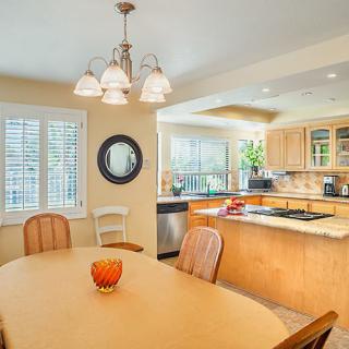 A cozy kitchen and dining area with a wooden table, chairs, and bright lighting.