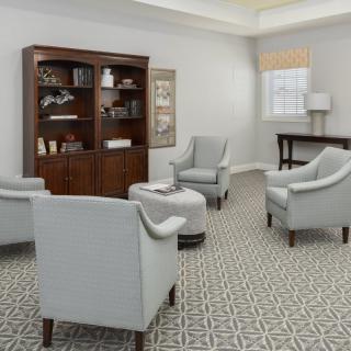 A cozy living room with armchairs, a bookshelf, and a patterned carpet.