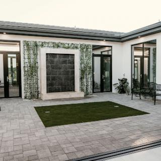 A contemporary courtyard featuring a stylish water wall, modern patio furniture, and lush greenery.