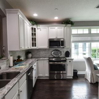 A modern kitchen with white cabinets and stainless steel appliances.