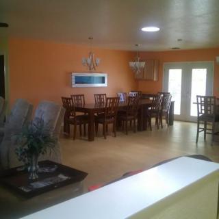 A spacious dining room with orange walls and a large dining table set.