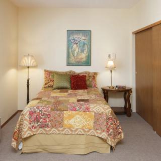 A cozy bedroom with a quilted bed, two lamps, and simple decor.