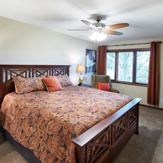 A cozy bedroom featuring a large bed with decorative bedding and natural light from the windows.