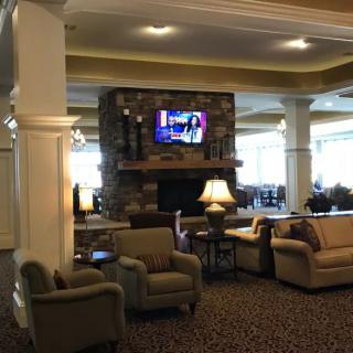 A cozy lobby interior with seating, a fireplace, and a television.