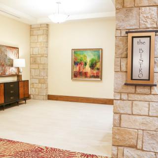 A well-lit lobby area with stone walls, featuring artwork and stylish furniture.