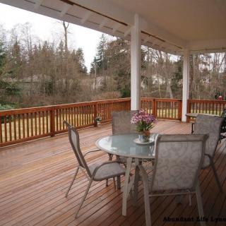 A spacious wooden deck with a table and chairs, surrounded by nature.